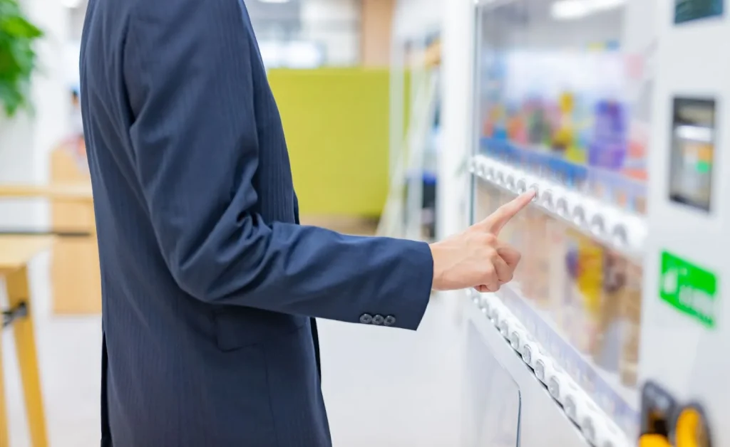 Một người đàn ông đang mua đồ uống từ máy bán hàng tự động