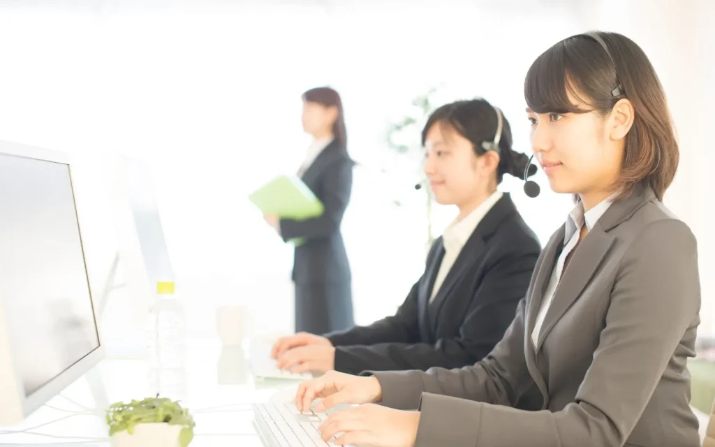 Bàn làm việc của một nhân viên dịch vụ khách hàng với máy tính và điện thoại.