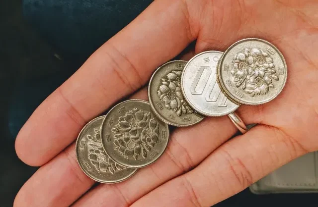 Một người phụ nữ đang cầm tiền xu 100 Yên